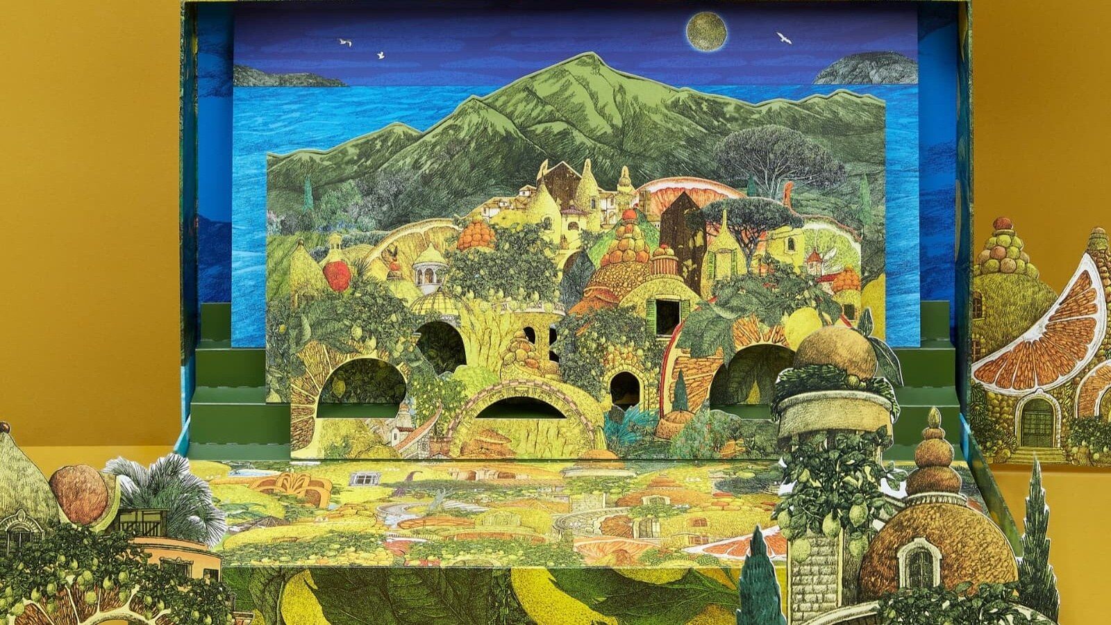 Le calendrier de l’Avent Alain Ducasse 2026 ouvert sur un village provençal illustré en relief, entre mer et montagne, sur fond moutarde