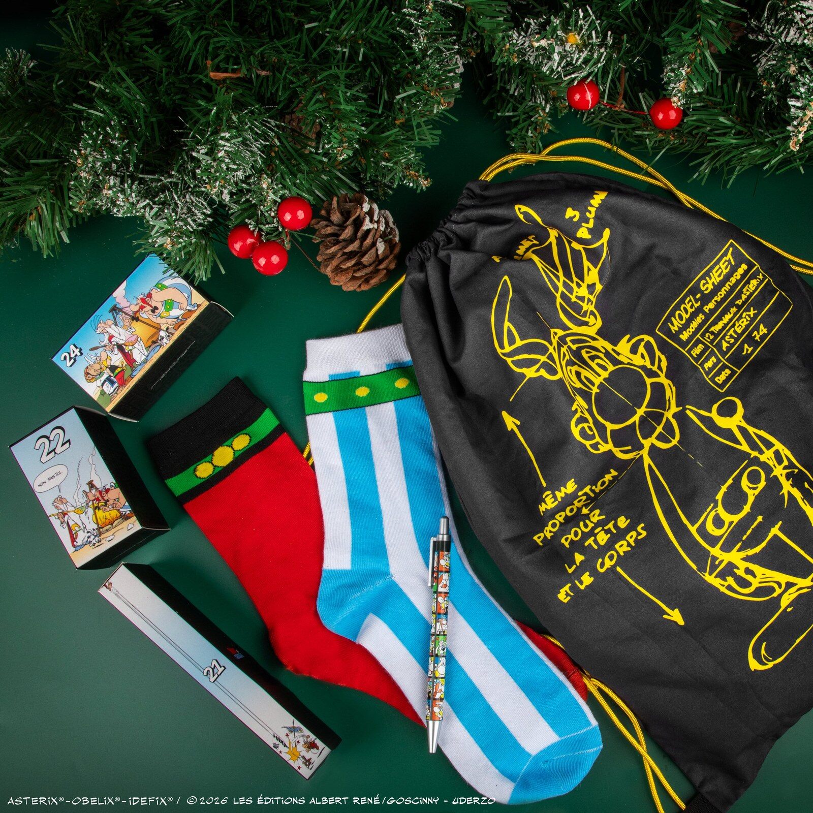 Chaussettes rayées d’Obélix, chaussette rouge, stylo et sac à cordon Astérix posés près d’un sapin