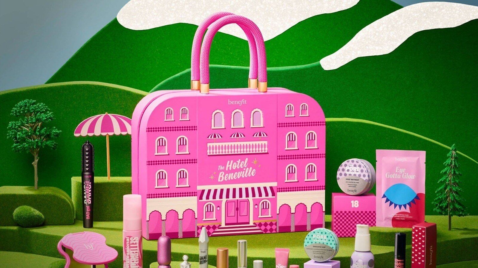 Le calendrier de l’Avent Benefit The Hotel Beneville 2026, vanity rose en forme d’hôtel, entouré de mascaras et de produits POREfessional dans un décor de collines