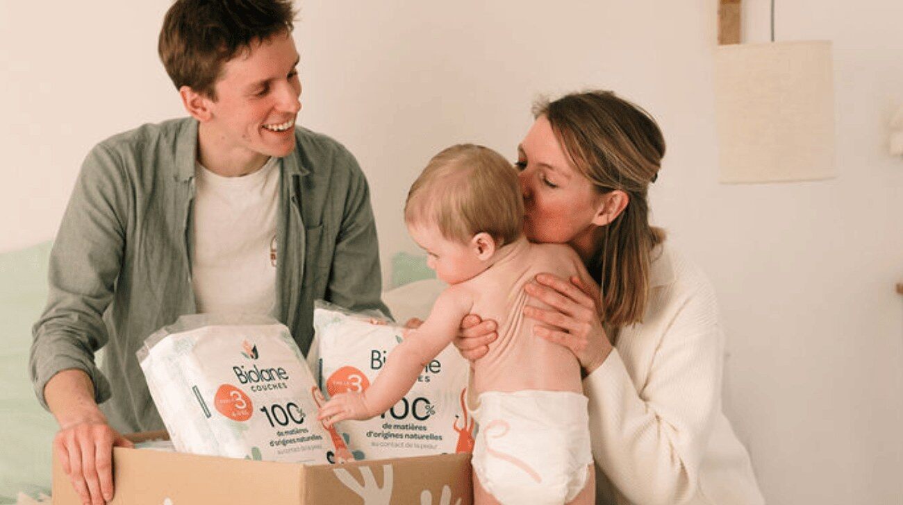 Parents et bébé autour d'un carton d'abonnement couches Biolane