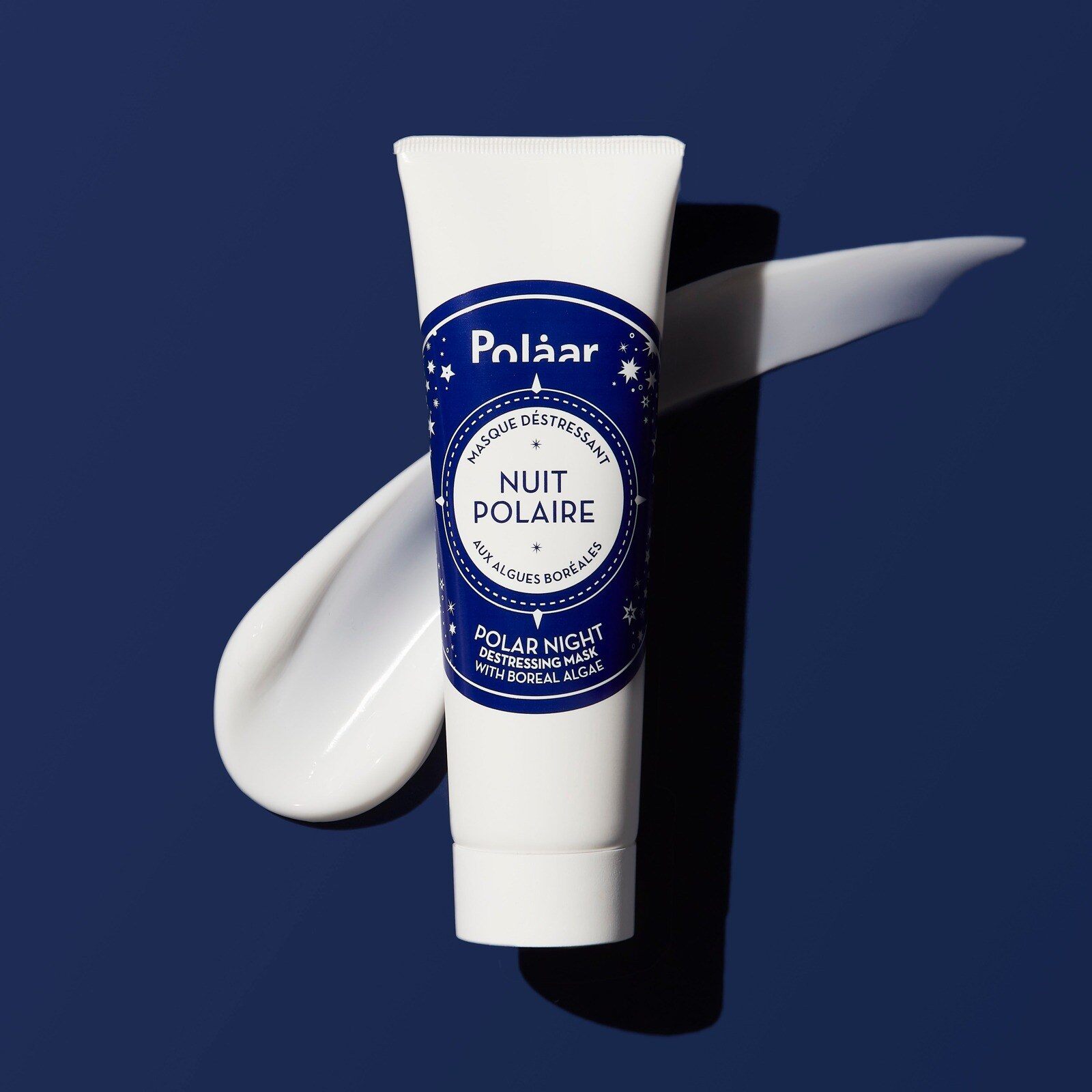 Tube du masque Nuit Polaire de Polaar posé sur une trace de texture blanche, sur fond bleu nuit