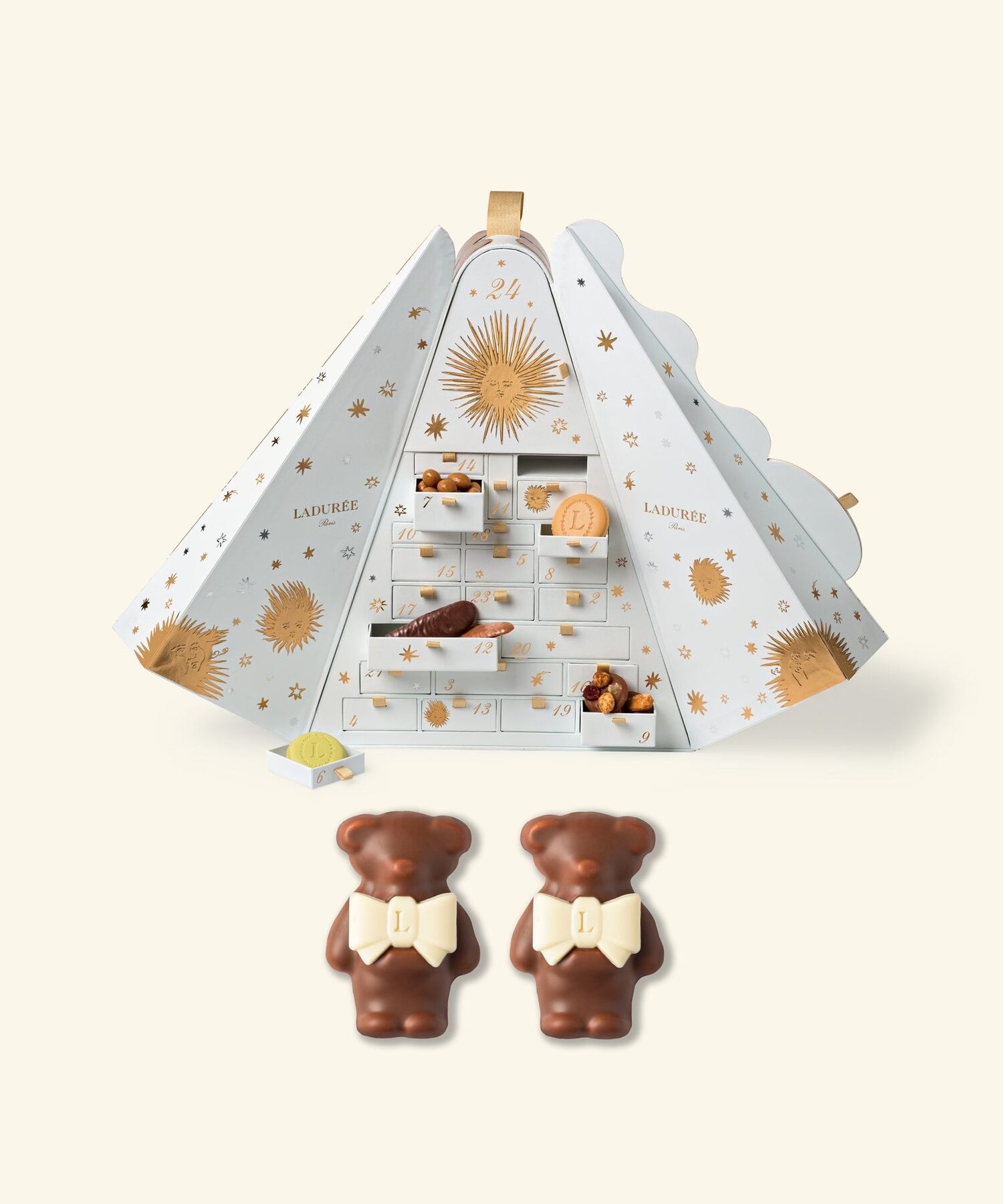 Le calendrier de l’Avent Ladurée 2026 ouvert, avec ses tiroirs blancs dorés remplis de chocolats, et deux oursons en chocolat posés devant