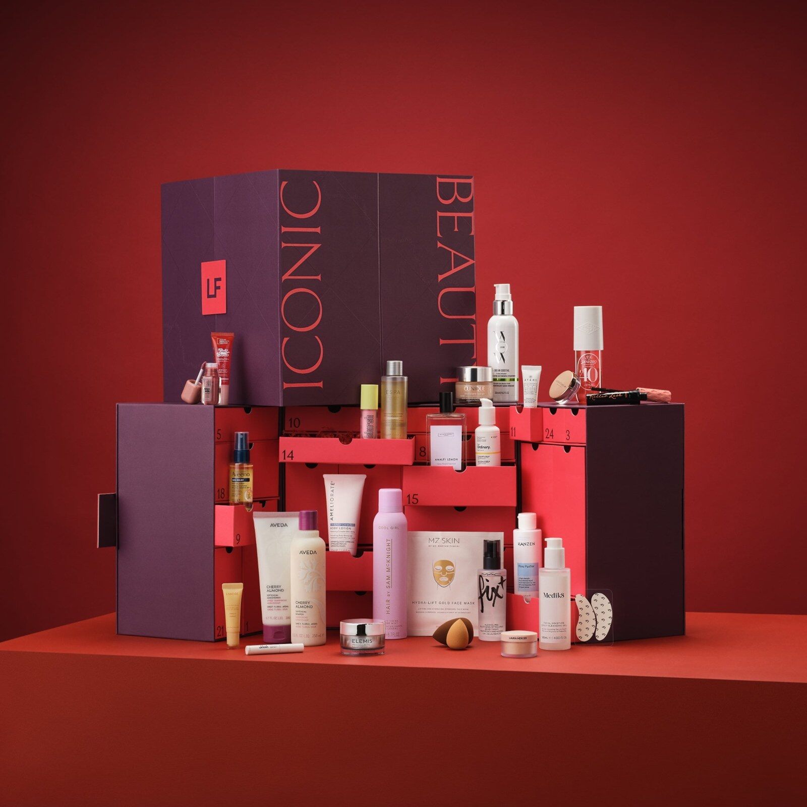 Le calendrier de l’Avent Lookfantastic 2026 ouvert, coffret prune et rouge marqué Iconic Beauty, entouré de ses produits sur fond rouge