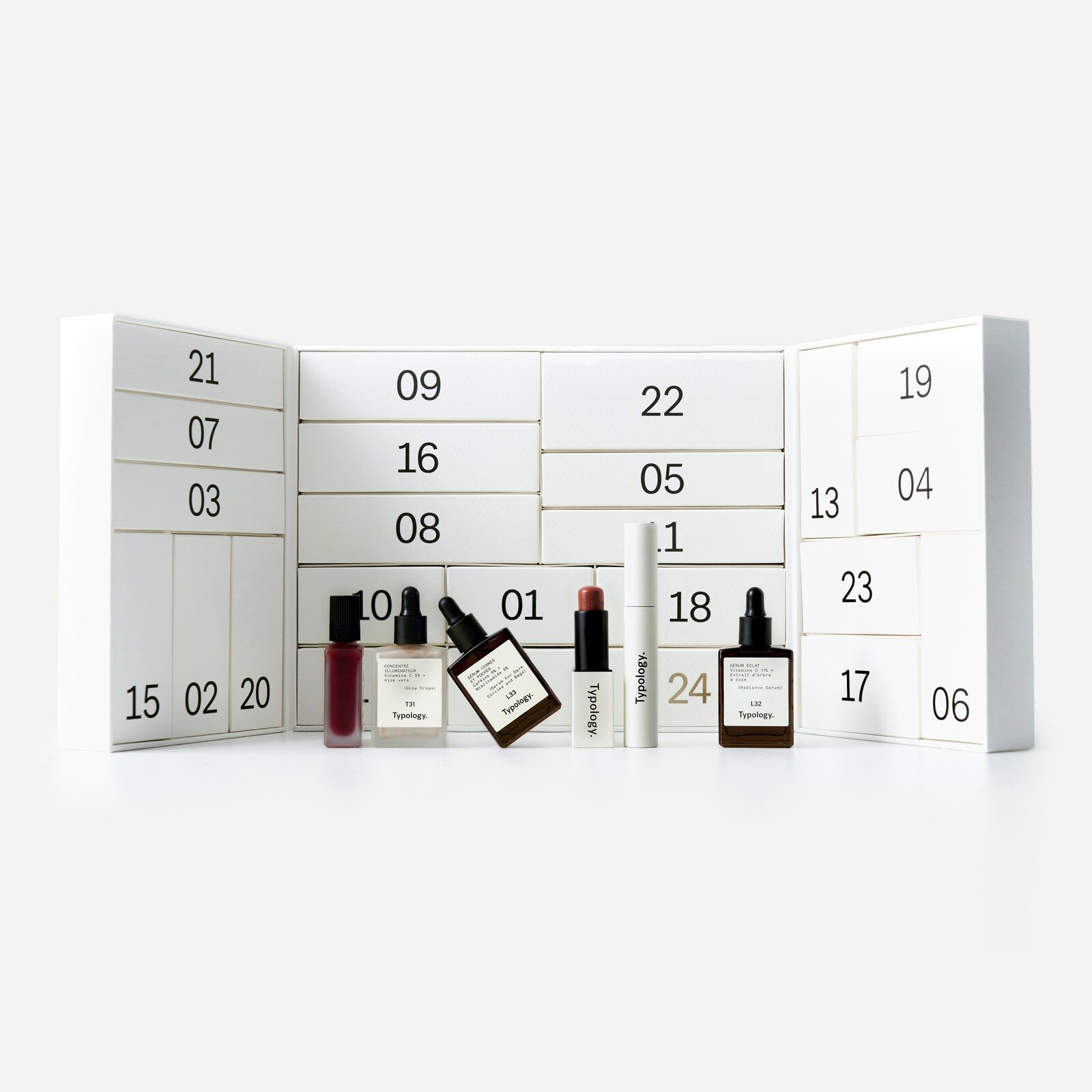 Le calendrier de l’Avent Typology 2026 ouvert, coffret blanc à tiroirs numérotés, avec des flacons de soins en verre ambré et un rouge à lèvres