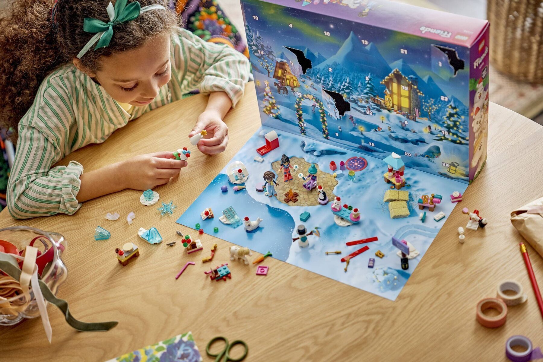 Une enfant joue avec les mini-poupées et les petites constructions du calendrier de l’Avent LEGO Friends 2026, devant sa boîte ouverte