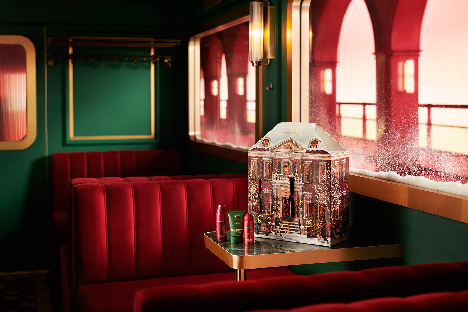 Le calendrier de l’Avent Classic Rituals 2026 en forme de maison enneigée, posé sur une table dans un wagon de train
