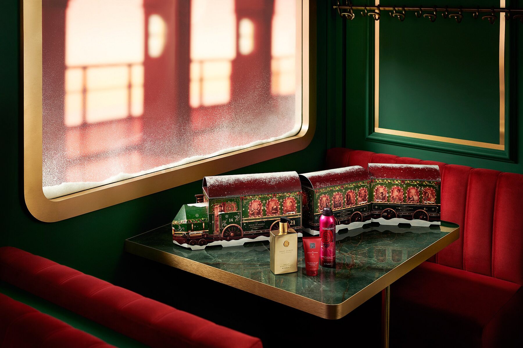 Le calendrier de l’Avent Premium Rituals 2026 en forme de train à trois wagons, sur une table avec plusieurs flacons Rituals