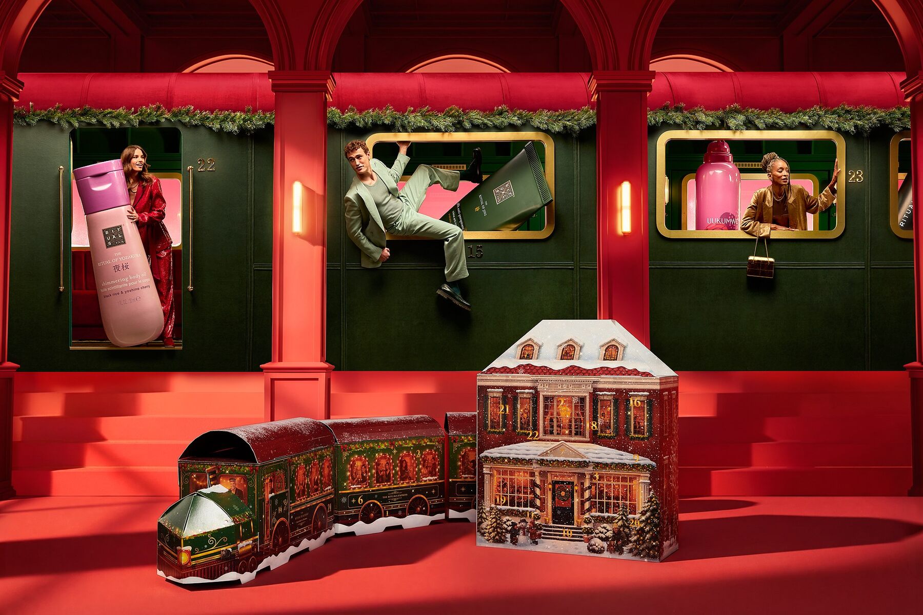 Le train du calendrier Premium et la maison du calendrier Classic Rituals 2026, devant un wagon de train décoré pour Noël