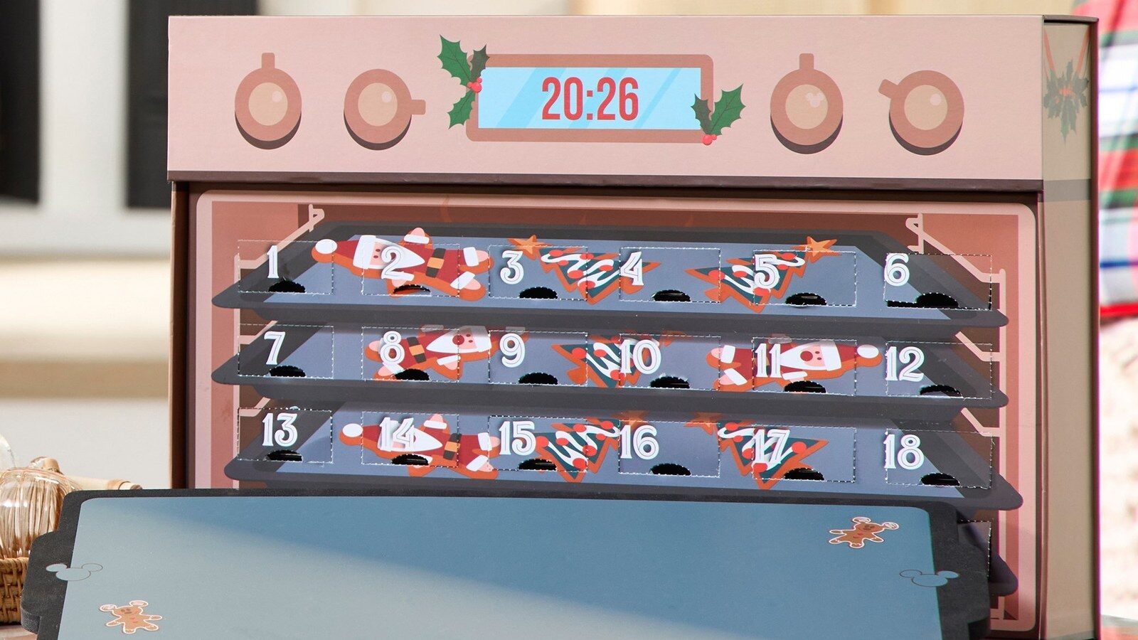 Le calendrier de l’Avent pin’s Disney 2026 en forme de four de Noël, posé sur une table, avec ses plaques de cuisson numérotées