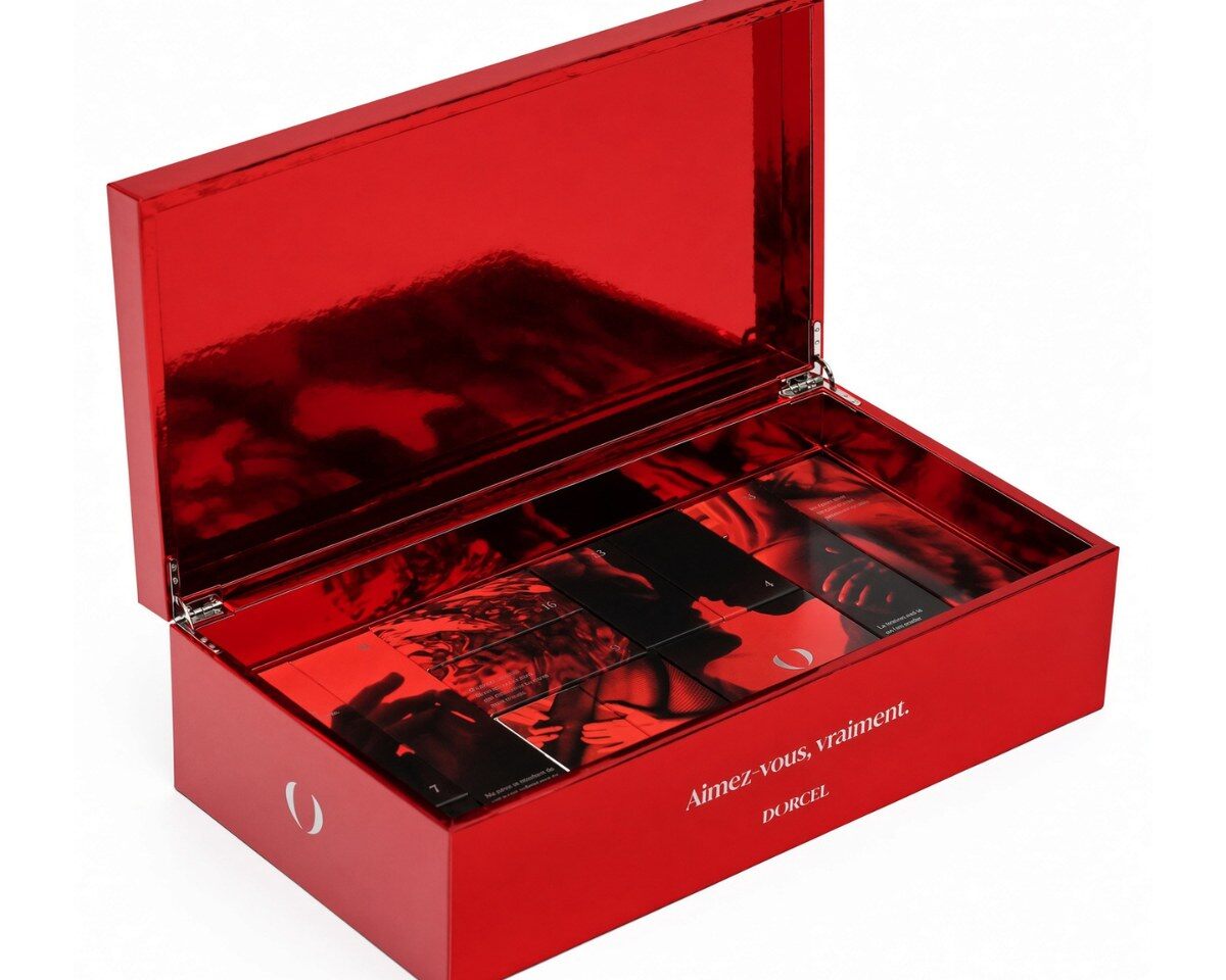 Coffret rouge du calendrier de l’Avent Dorcel 2026 ouvert, cases fermées illustrées de photos et de phrases