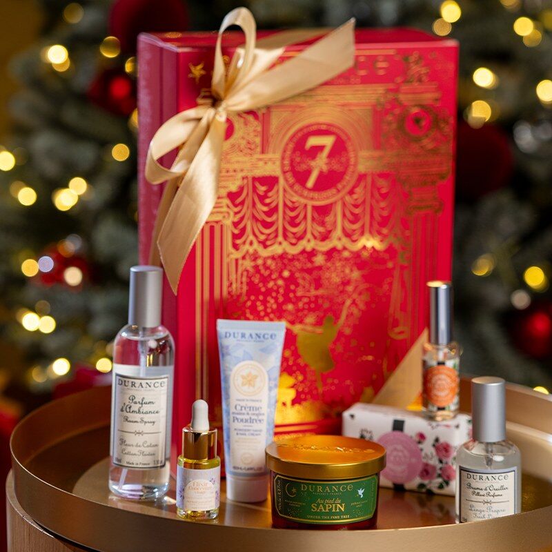 Le calendrier de l’Après Durance devant un sapin illuminé, entouré de ses produits : parfum d’ambiance, bougie, brume, crème et eau de toilette