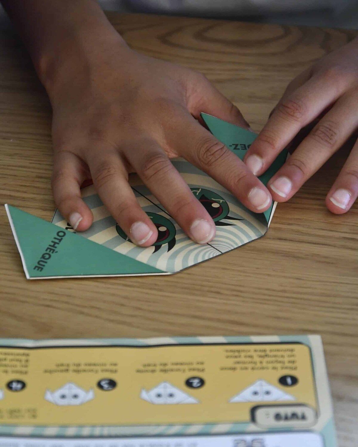 Un enfant manipule des fiches d’énigmes imprimées d’un escape game d’Halloween