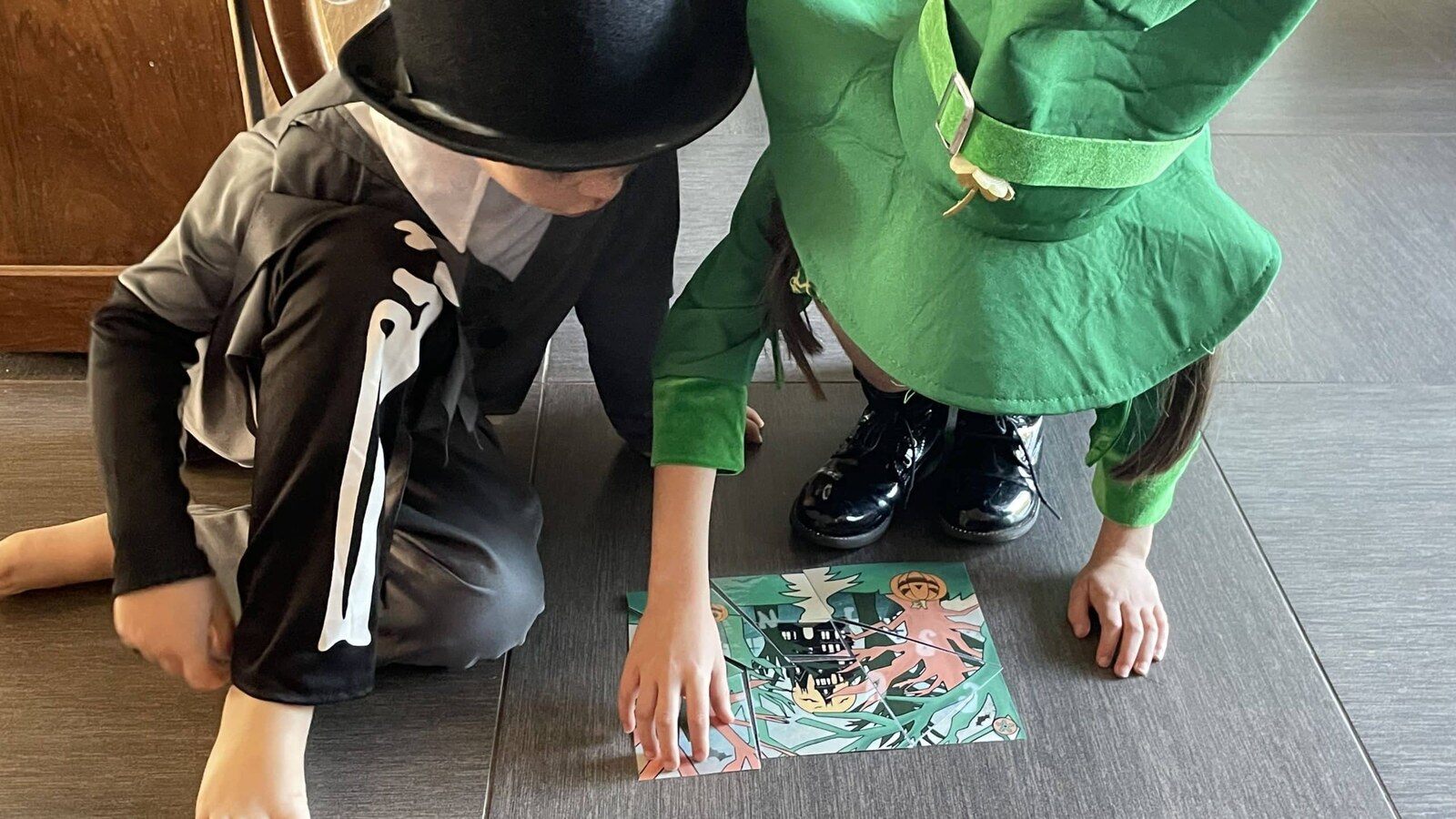 Deux enfants déguisés pour Halloween résolvent une énigme imprimée posée au sol