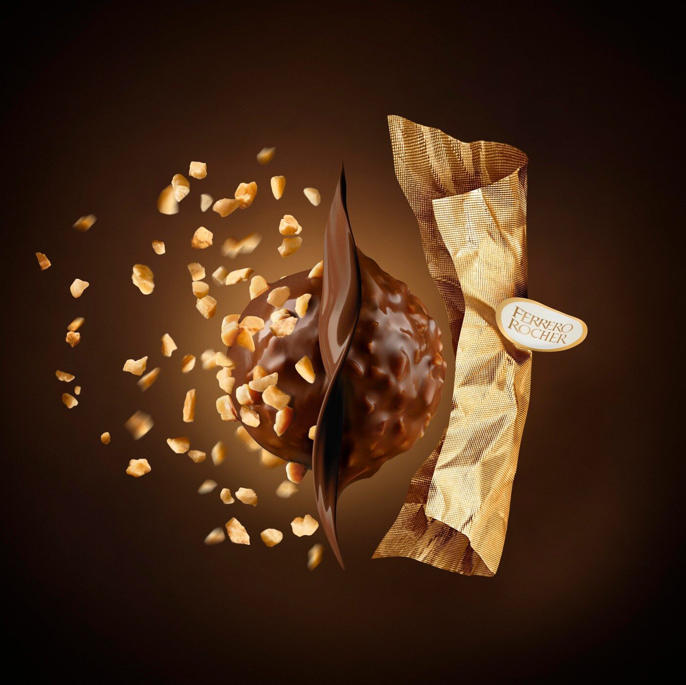 Une bouchée Ferrero Rocher coupée en deux, entourée d’éclats de noisettes et de son papier doré