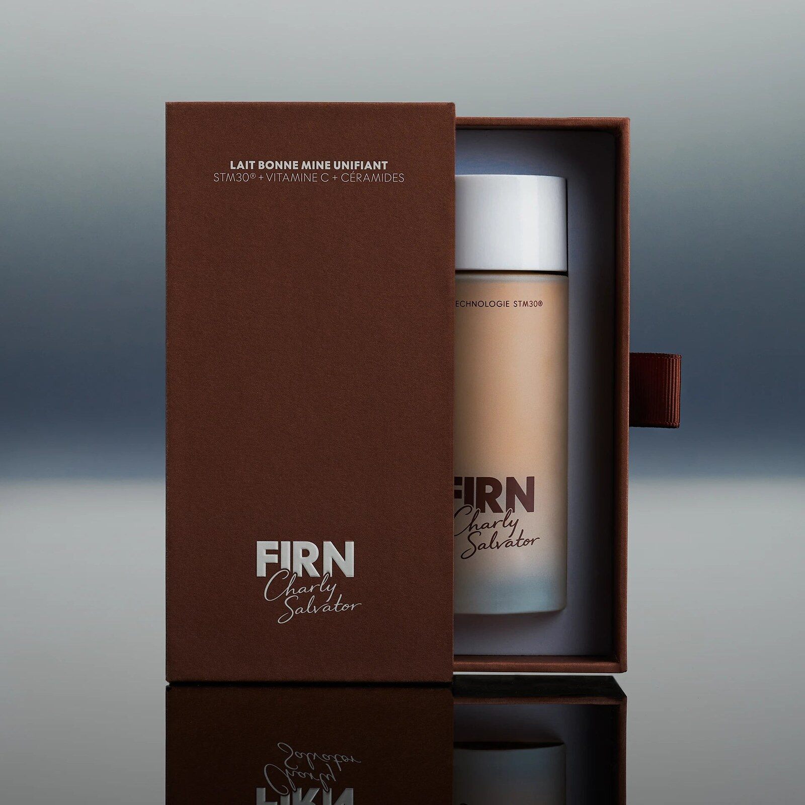 Flacon du Milk Teinté Charly Salvator x FIRN sortant de sa boîte marron