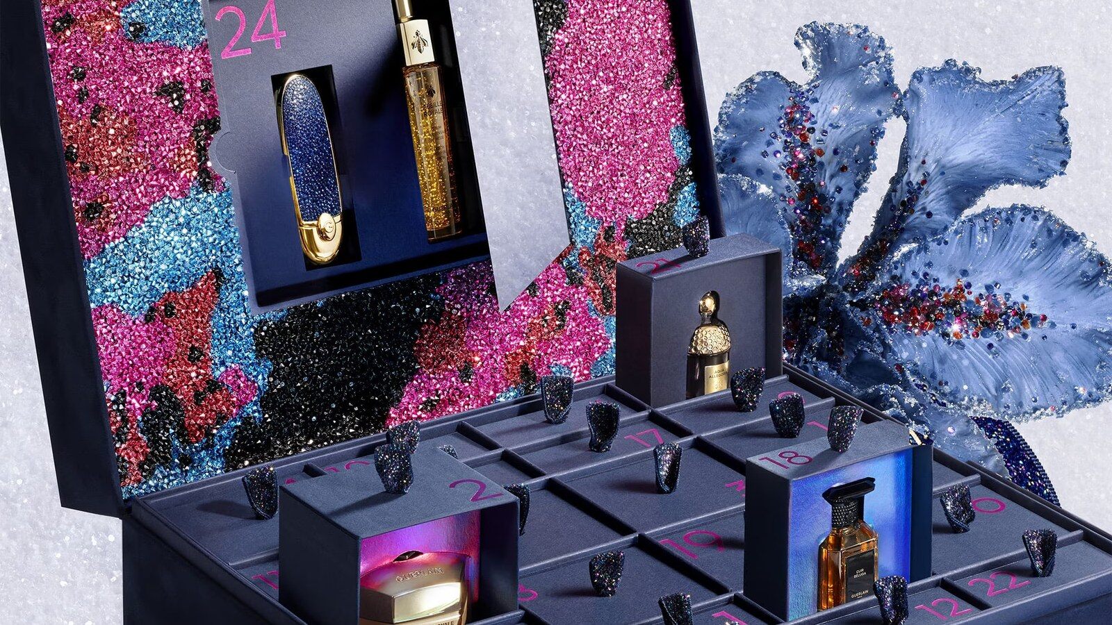 Calendrier de l’Avent Guerlain x Germanier 2026 ouvert, tiroirs numérotés et intérieur scintillant sur fond pailleté bleu