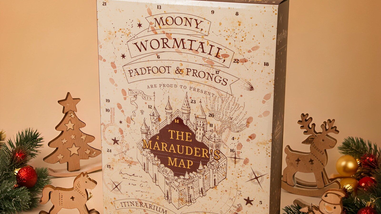 Le calendrier de l’Avent Harry Potter Carte du Maraudeur 2026 de Cinereplicas posé entre un sapin en bois, un renne et des boules de Noël