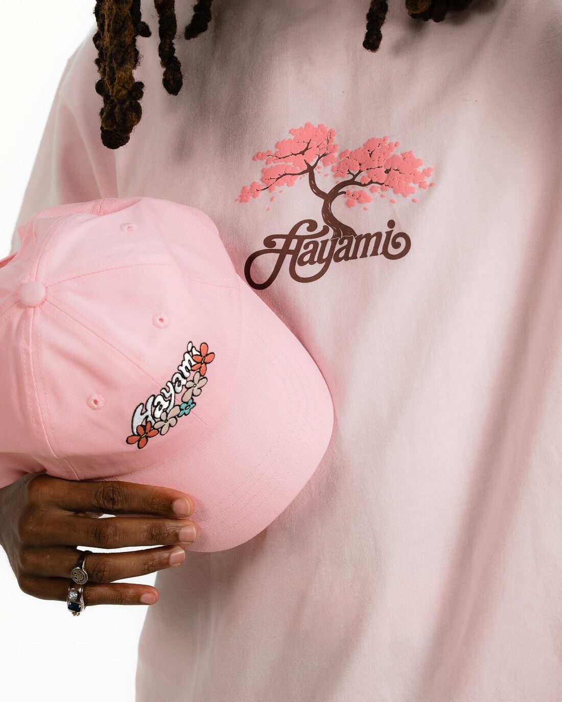 T-shirt rose brodé d’un cerisier Hayami et casquette rose tenue à la main