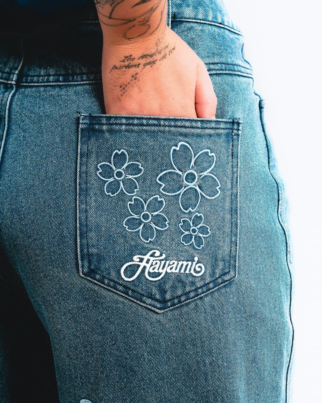 Poche arrière d’un jean brodée de fleurs de cerisier et du logo Hayami