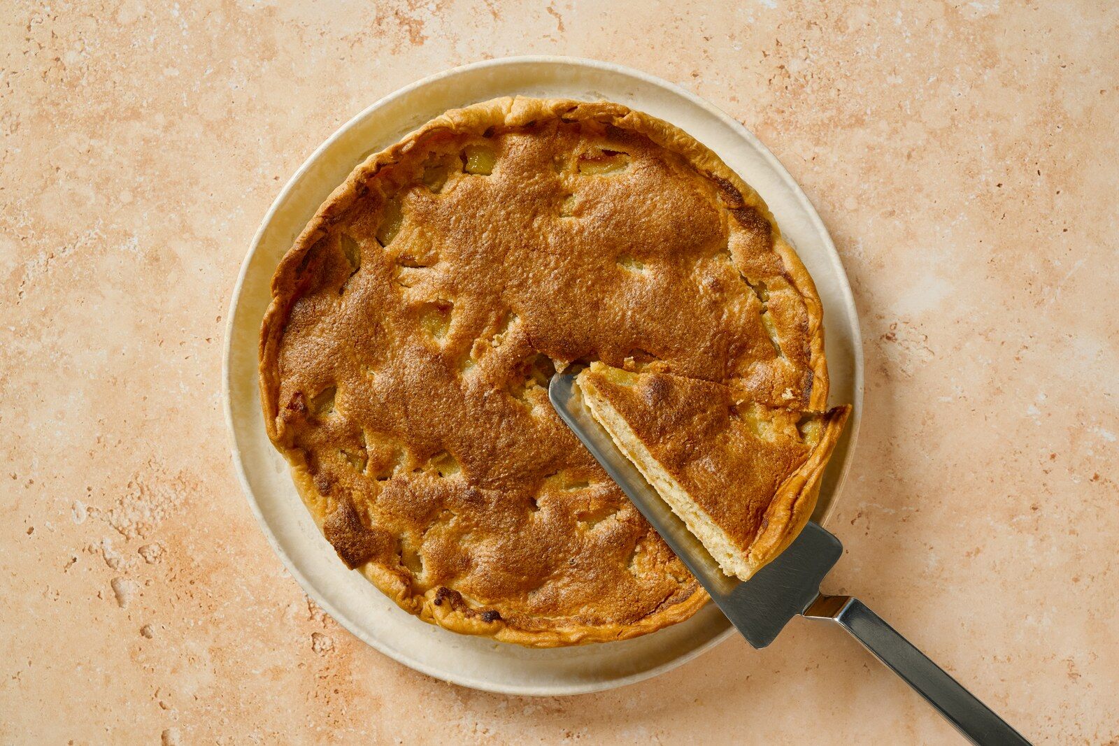 Tarte Bourdaloue aux poires et à la crème d’amande, une part soulevée avec une pelle à tarte