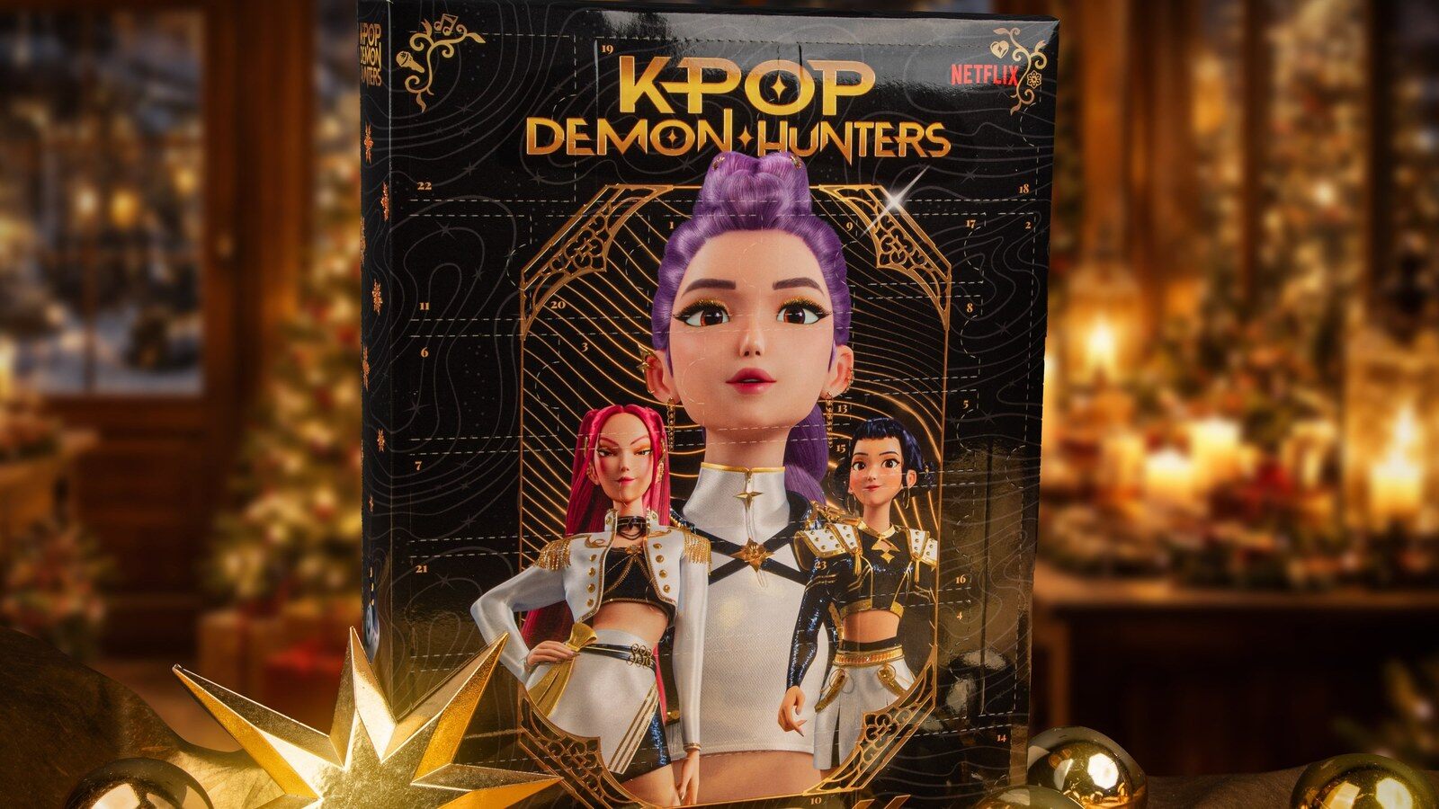 Le calendrier de l’Avent KPop Demon Hunters 2026 avec Rumi, Mira et Zoey, posé devant un sapin et des boules de Noël dorées