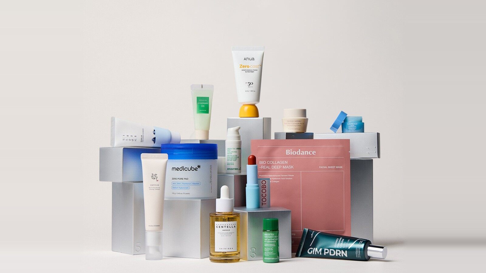 Les produits du calendrier 12 jours K-beauty Lookfantastic posés sur des cubes : Anua, Medicube, Biodance, SKIN1004, Laneige, Tocobo et Isntree