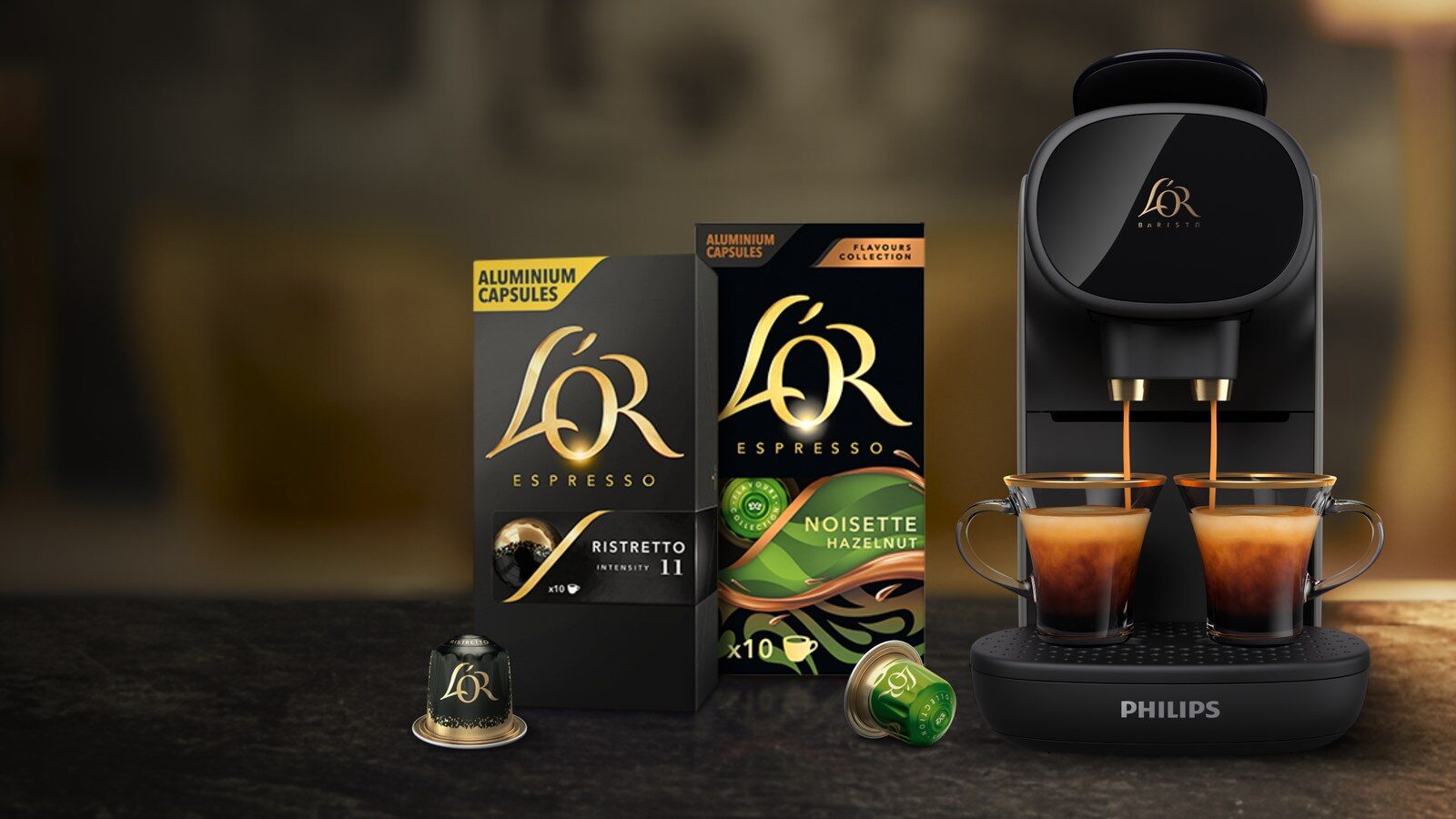 Capsules et boîtes L’Or Espresso devant une machine L’OR Barista qui sert deux cafés, dans une cuisine tamisée
