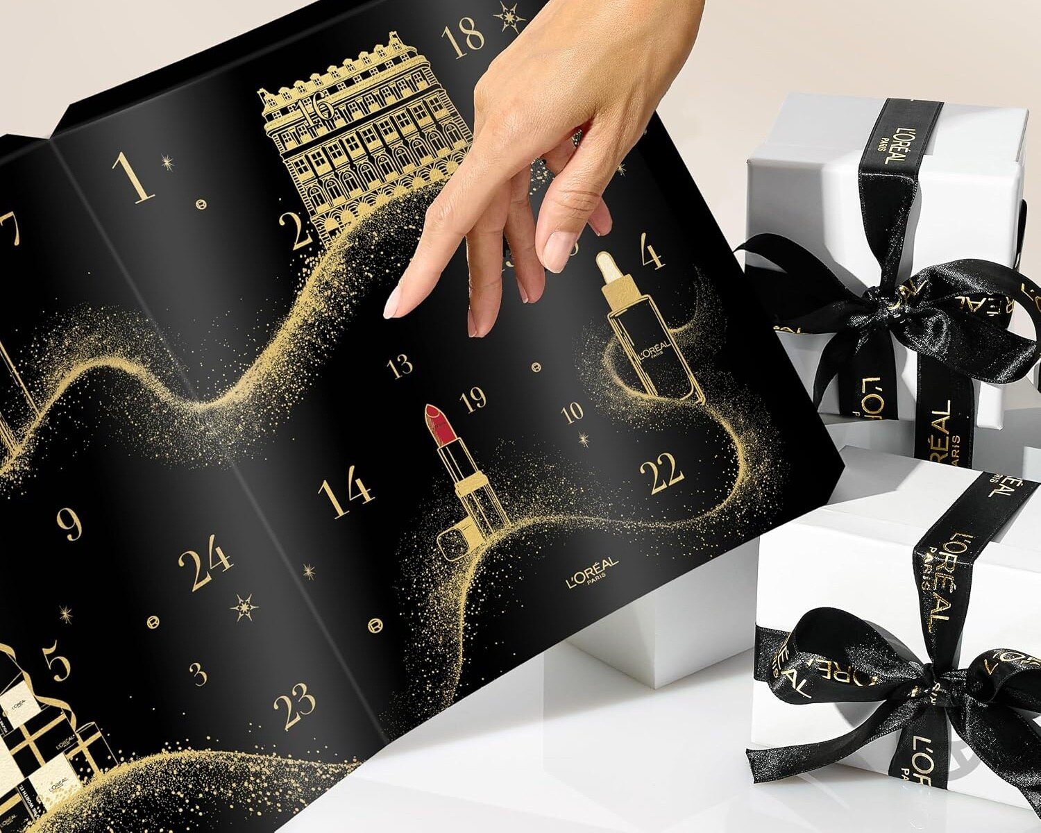 Une main ouvre une case du calendrier de l’Avent L’Oréal Paris 2026, à côté de paquets cadeaux