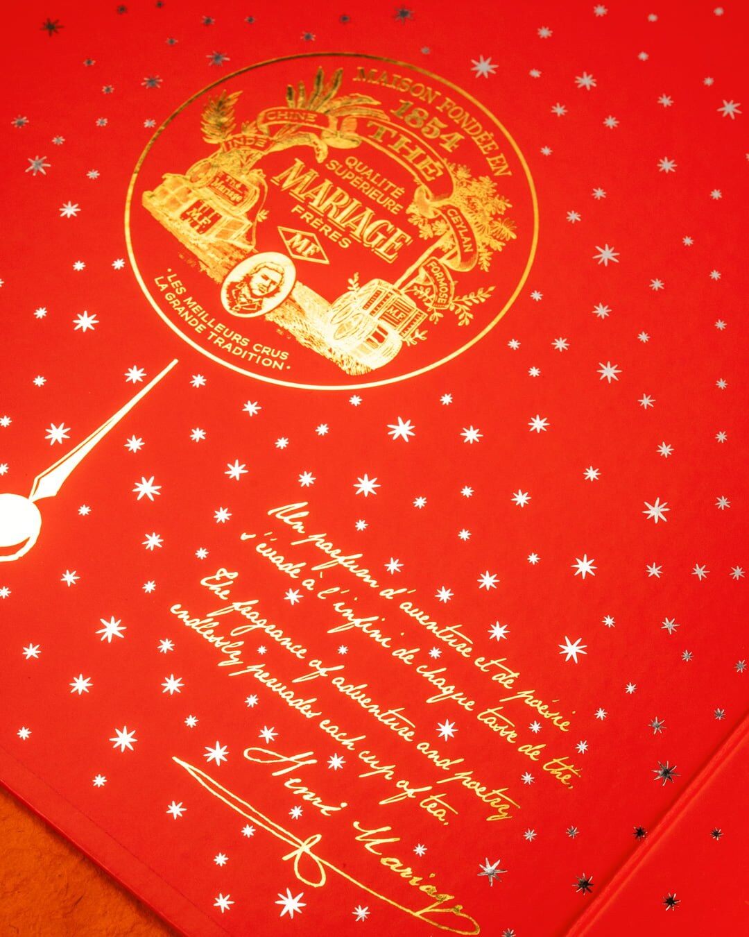 Intérieur de l’écrin Mariage Frères orange et or, décoré d’étoiles et d’un texte manuscrit de la maison