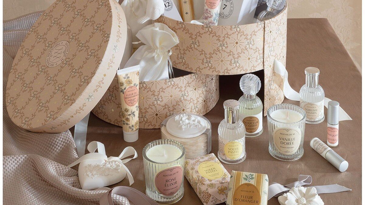 Le calendrier de l’Avent Mathilde M Rubans de Fête ouvert sur une table, entouré de bougies, parfums, savons et baumes mains