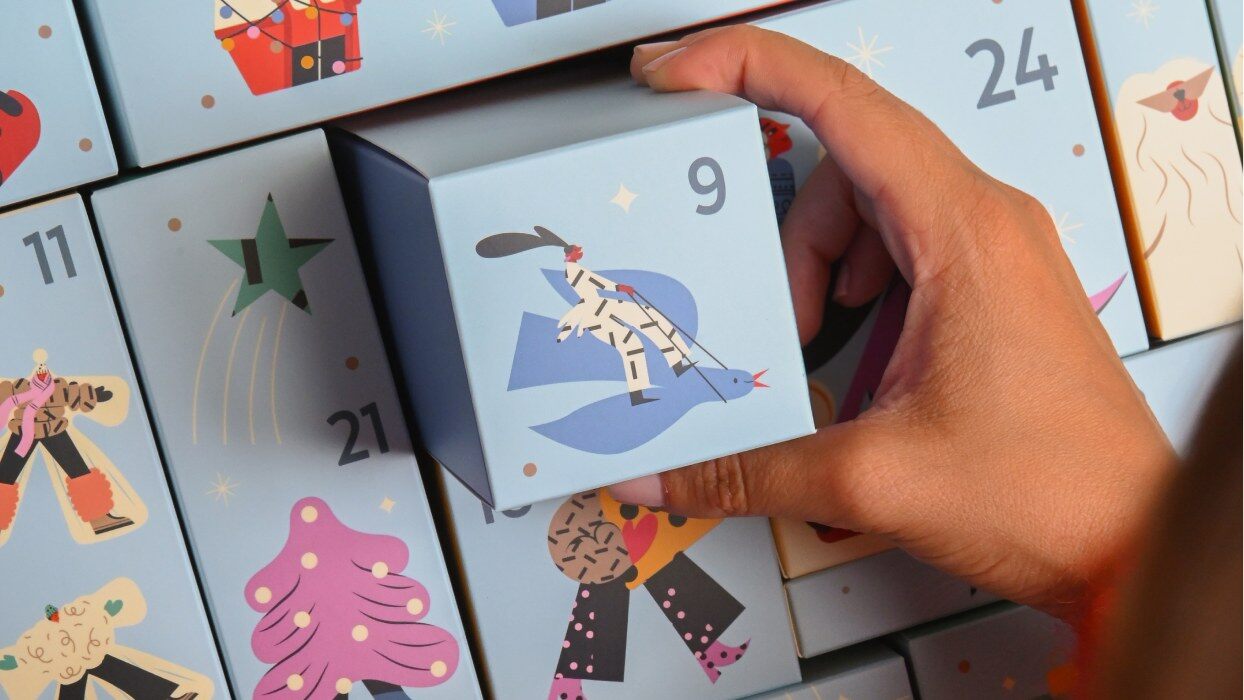 Une main tire la case 9 du calendrier de l’Avent My Jolie Candle 2026, illustrée d’un skieur