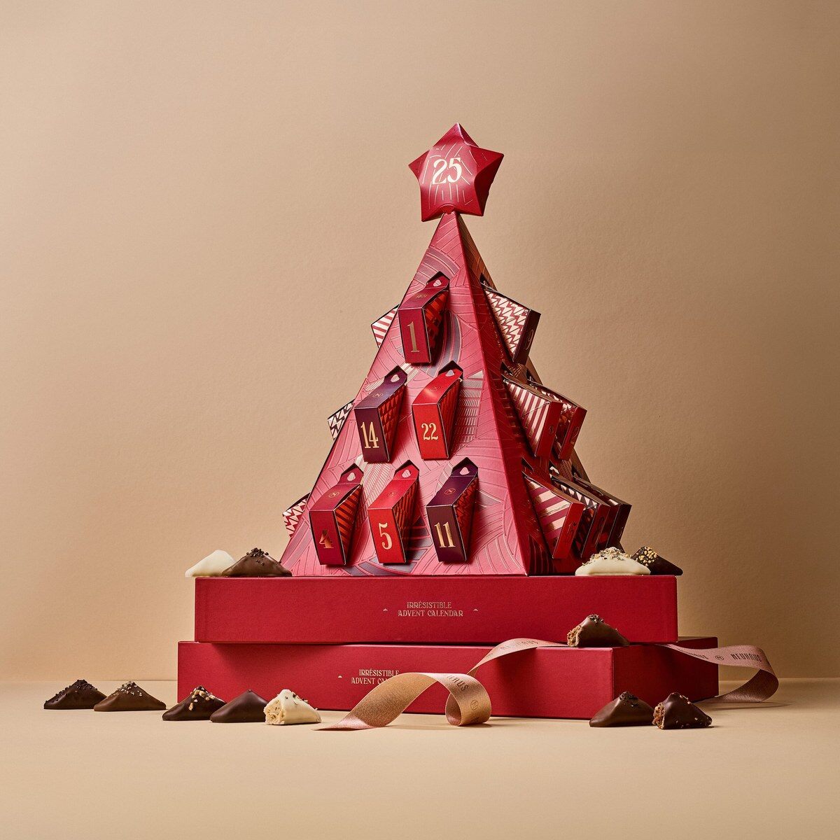 Le calendrier L’Irrésistible de Neuhaus déplié en sapin rouge, sur son coffret, entouré de chocolats