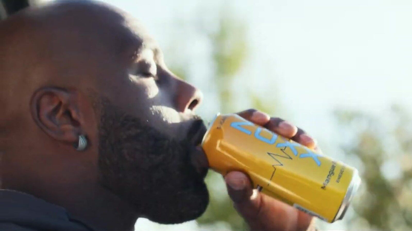 Teddy Riner boit une canette jaune de Noxx en plein air