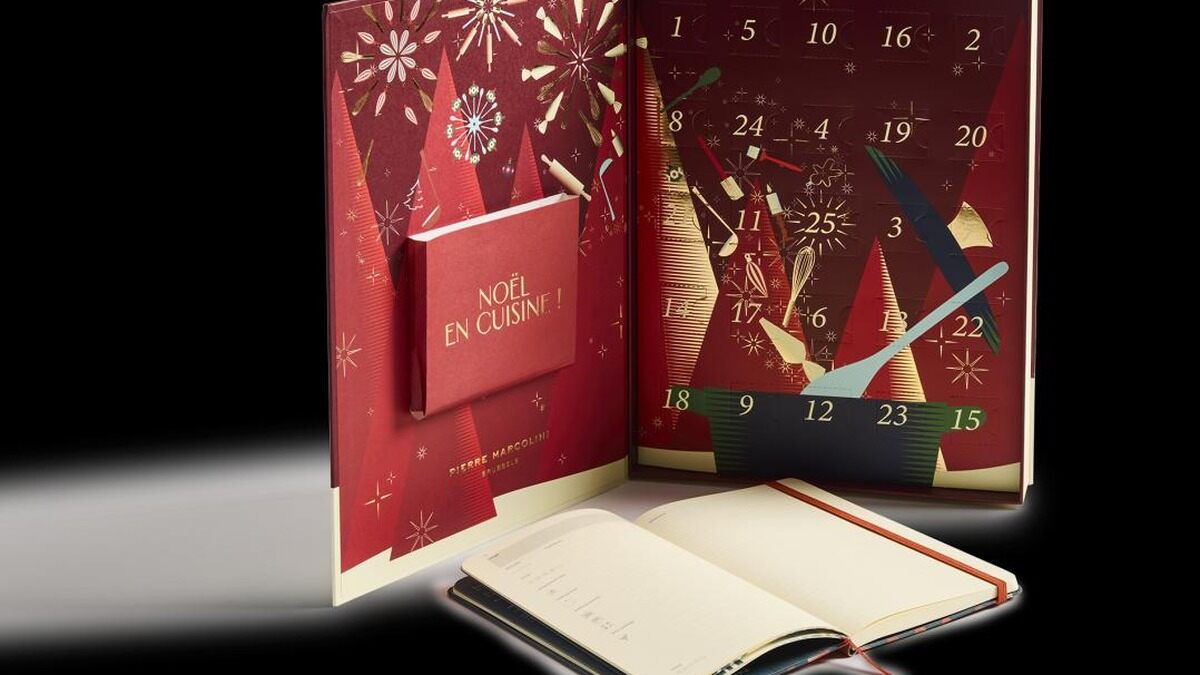 Le calendrier de l’Avent Pierre Marcolini Noël en cuisine ouvert, posé derrière un carnet Moleskine ouvert