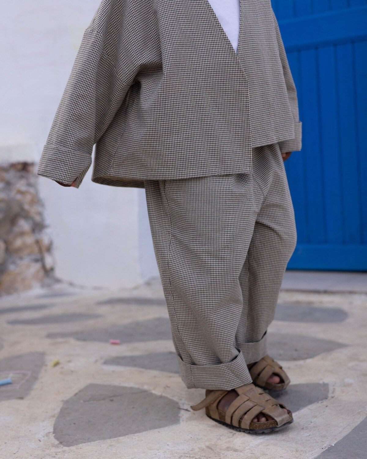 Enfant portant l’ensemble pied-de-poule Hazel de RAÏSHA devant une porte bleue