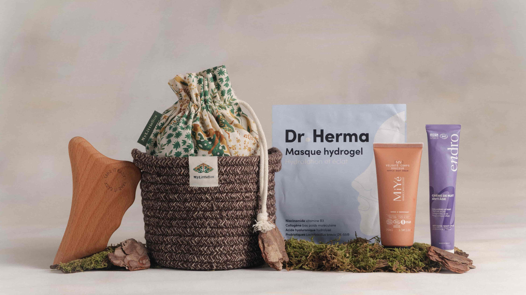 Visuel officiel de la My Little Box d’octobre 2026 « Murmures des bois » : un panier en osier et son pochon à motif végétal, entourés du masque hydrogel Dr Herma, de la crème de nuit Endro et d’un soin corps MiYé.