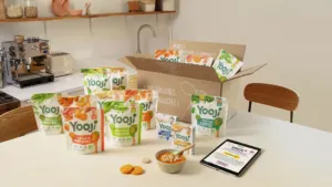 Colis Yooji ouvert et sachets de purées bébé surgelées sur une table de cuisine