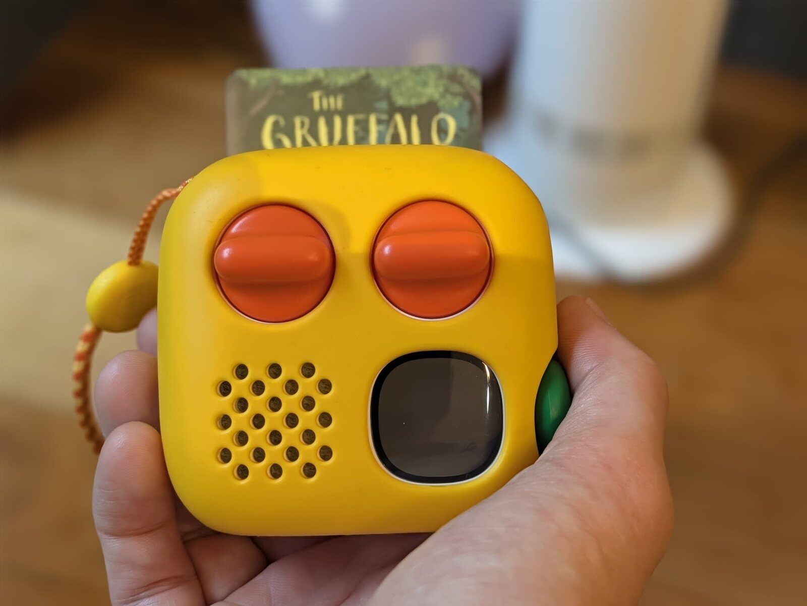 Yoto Mini 4e génération jaune tenue dans la main, carte Le Gruffalo insérée, avec ses deux boutons orange et le bouton vert